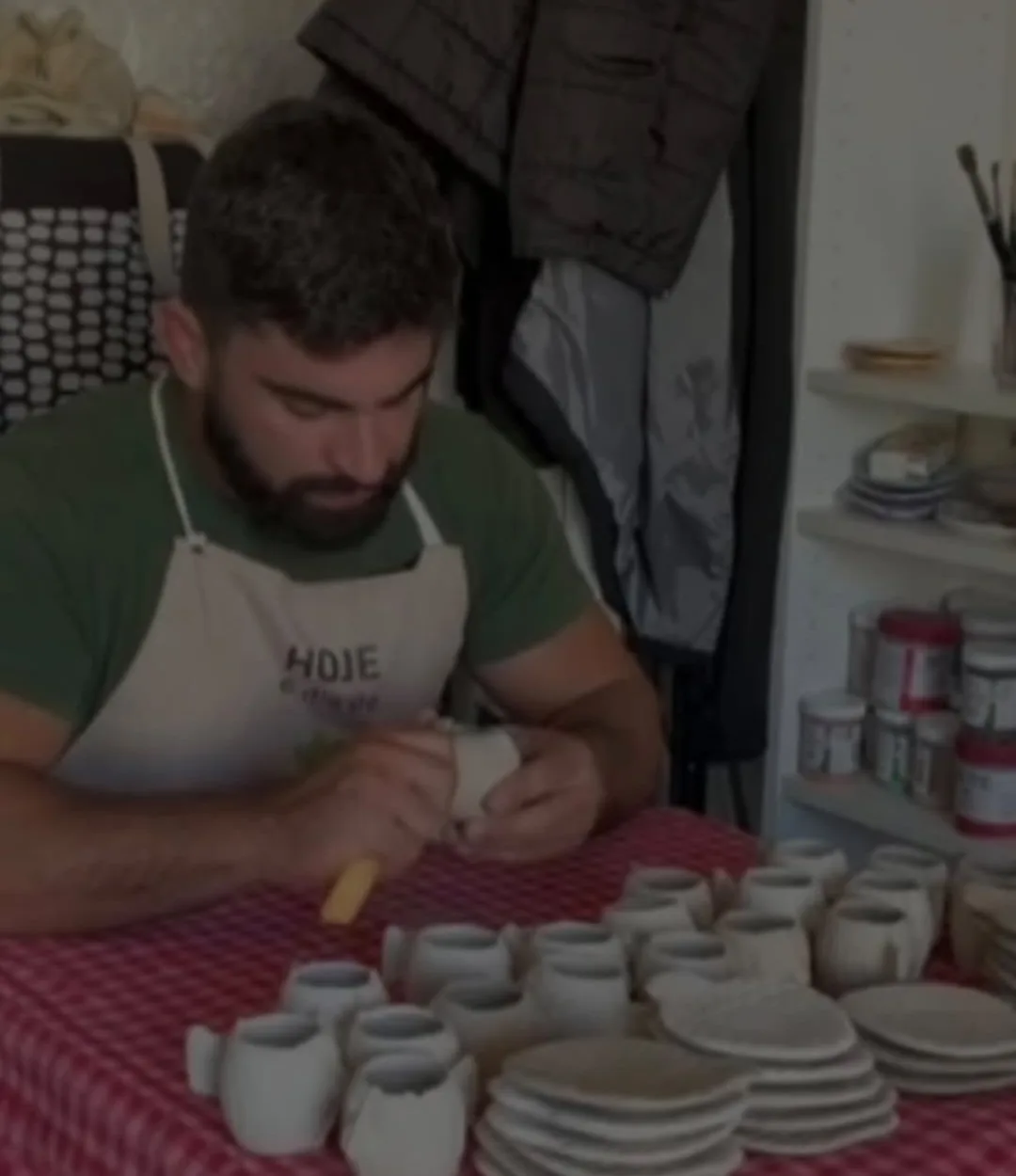 O Augusto a moldar copos numa mesa com toalha aos quadrados vermelhos