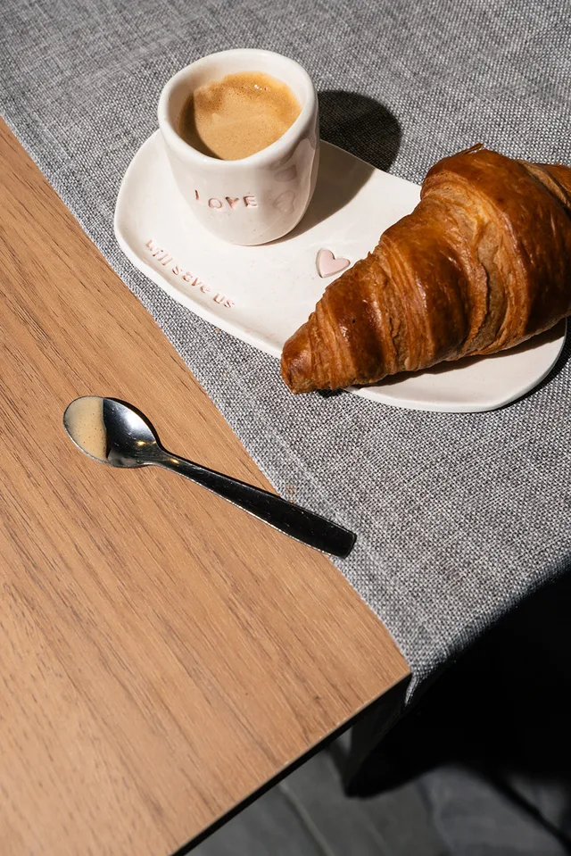 Copo Camélia com café e um croissant